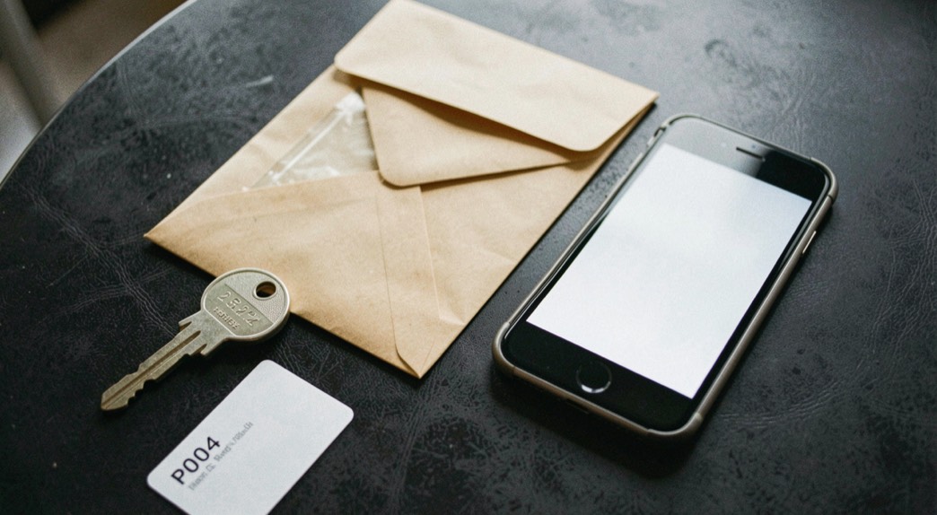 Documentary photograph of a spare security key, a sealed envelope and a phone with a blank screen on a dark table, no readable text, careful side light. Distinct supporting card P004 3 composition for this editorial entry.