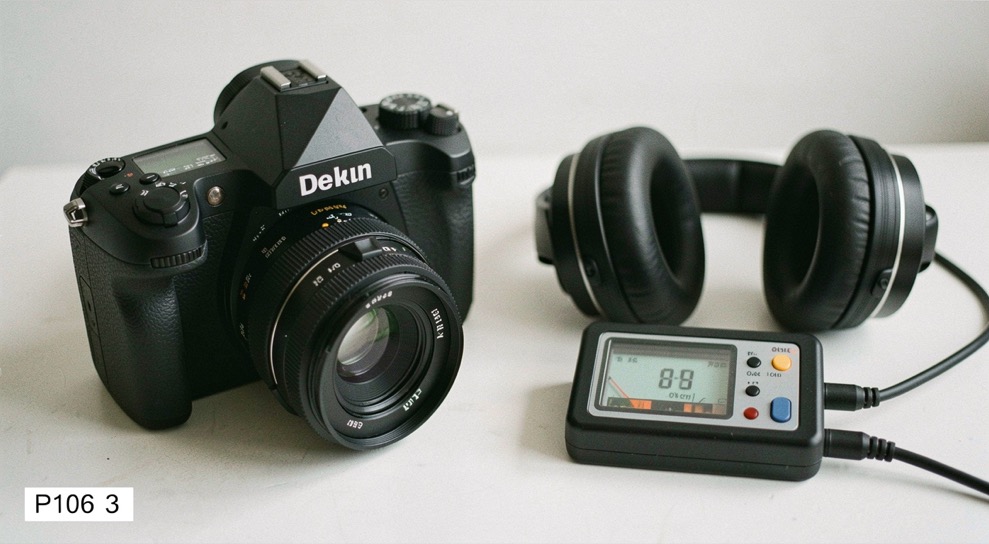 Documentary photograph of a camera, microphone, headphones and a small audio meter ready for a test recording, no visible labels or screens, clean studio light. Distinct supporting card P106 3 composition for this editorial entry.